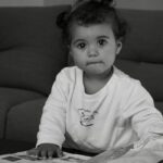Enfant feuilletant un cahier de vacances coloré sur une table de jardin ensoleillée