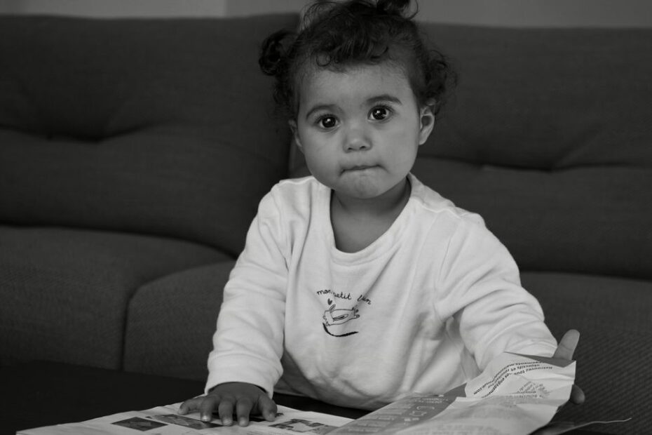 Enfant feuilletant un cahier de vacances coloré sur une table de jardin ensoleillée