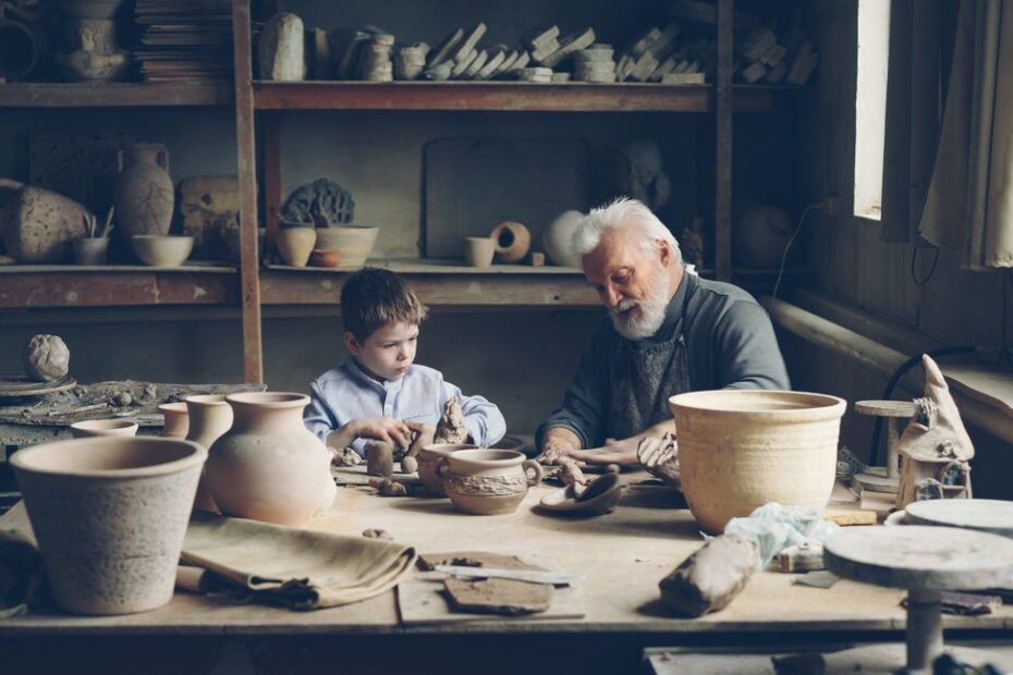 Enfants en famille qui peignent de la céramique lors d'un atelier créatif en vacances