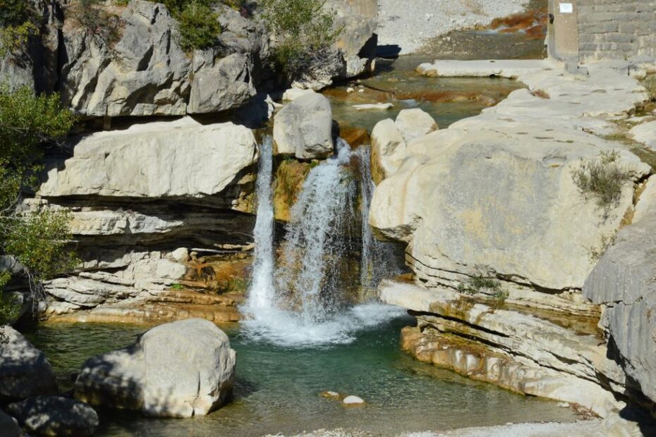 Gouffre de Fontaine-de-Vaucluse avec eau turquoise jaillissant au pied de la falaise calcaire en Provence