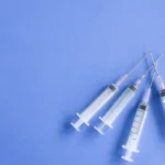 Seringue préremplie de vaccin posée sur une table médicale blanche