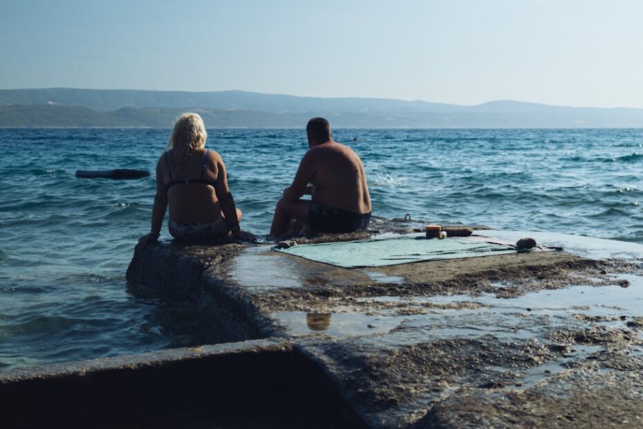 Couple enlacé sur une terrasse d'hôtel face à la mer au coucher du soleil