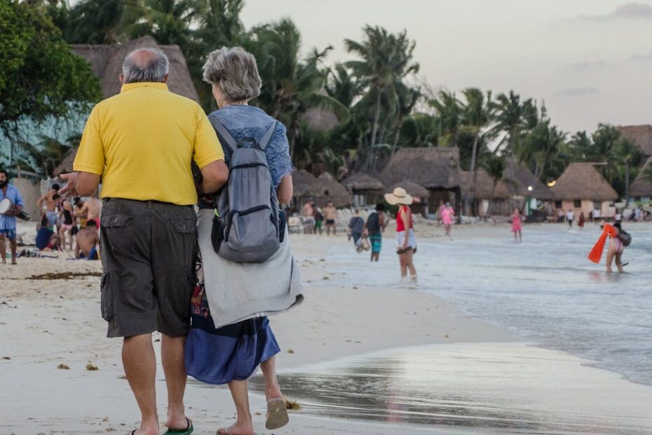 Couple de retraités souriants devant un village vacances en bord de mer