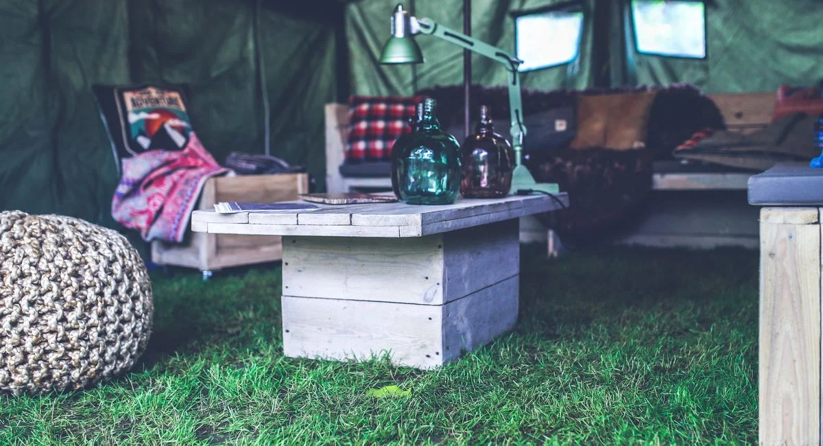 A cozy indoor tent decorated with rustic furniture, perfect for camping vibes.