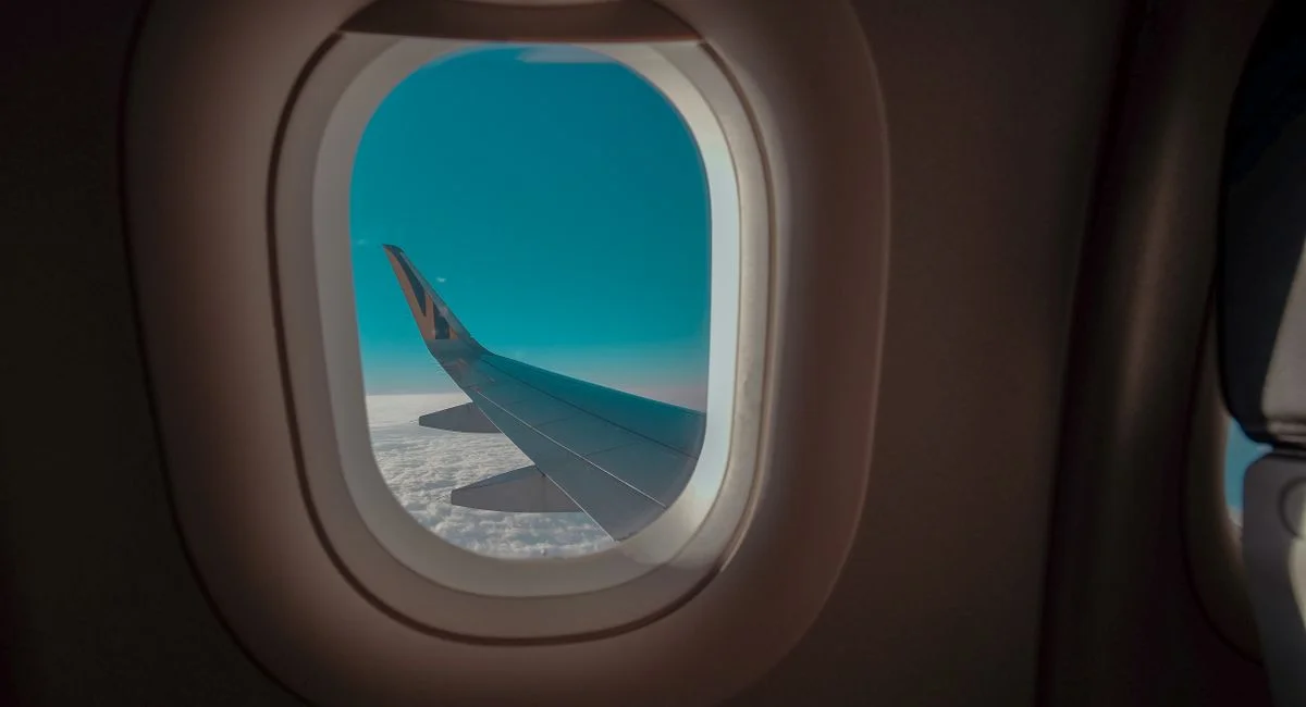 A picturesque view of an airplane wing from the cabin window, soaring above the clouds.