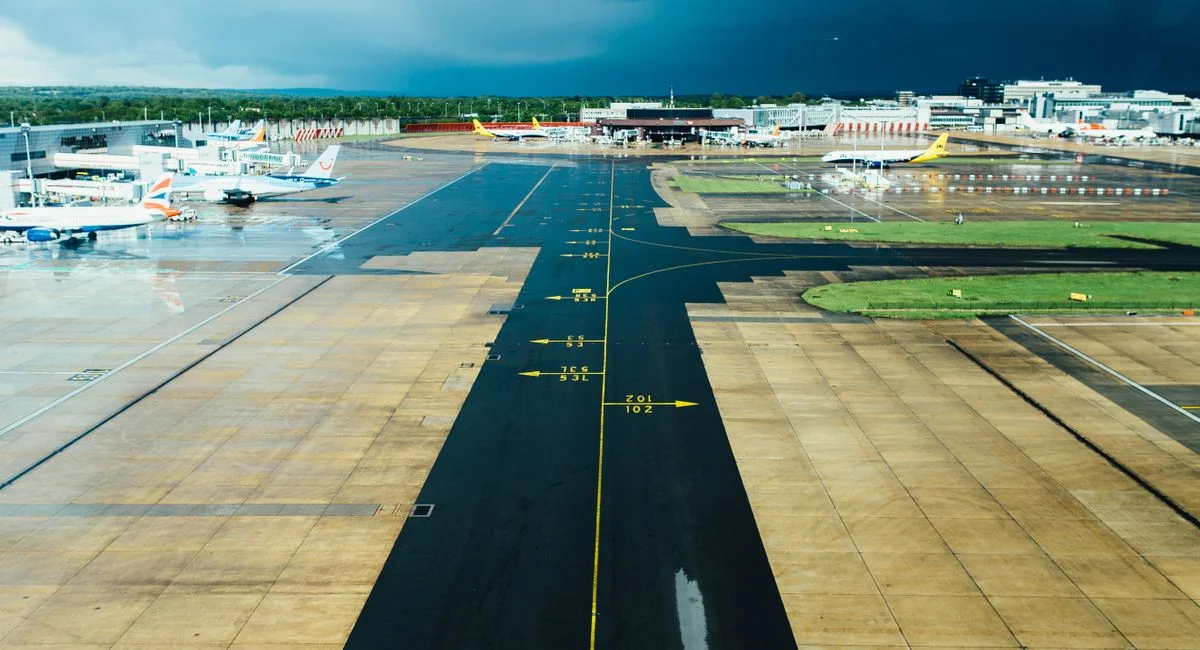 Aerial view of an airport runway with several parked planes on a cloudy day. Ideal for travel and aviation themes.