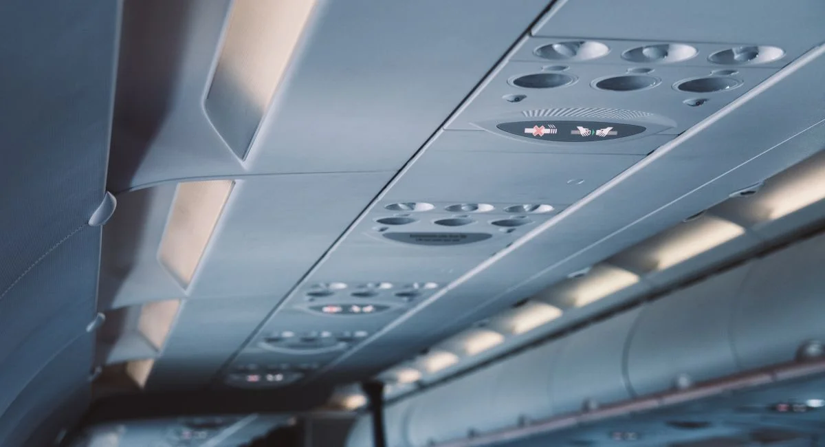 Close-up view of an airplane ceiling panel featuring overhead lights and air vents.