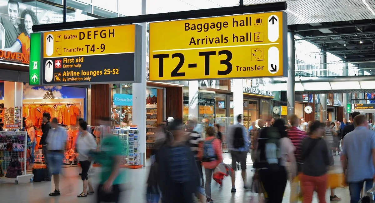 Crowded airport with motion blur and clear signage indicating baggage and arrival halls.