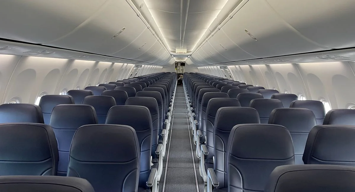 Interior of a modern airplane with empty rows and elegant seating, highlighting comfort and spacious design.
