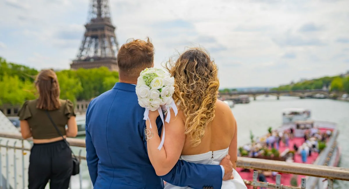 Newlyweds embracing by the Seine River with the Eiffel Tower in the backdrop, Paris.