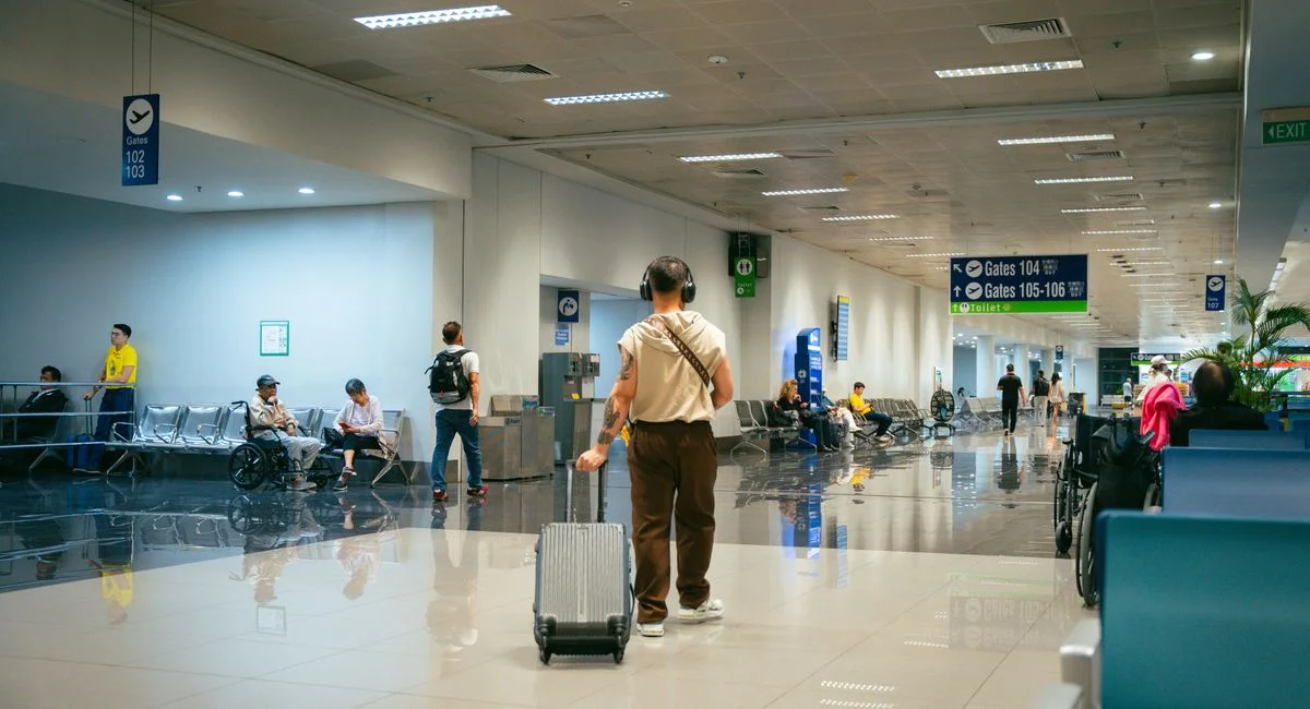 Passengers in a spacious airport terminal, some seated and others walking.