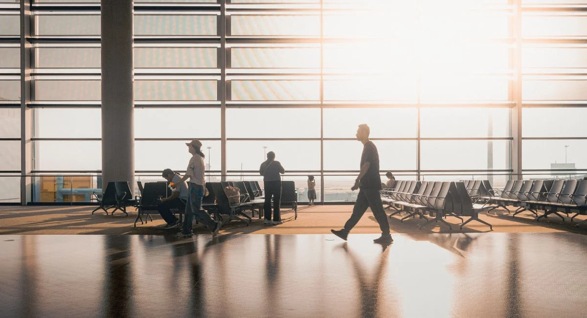 Silhouetted figures move through a sunlit Shanghai airport terminal, capturing travel's essence.