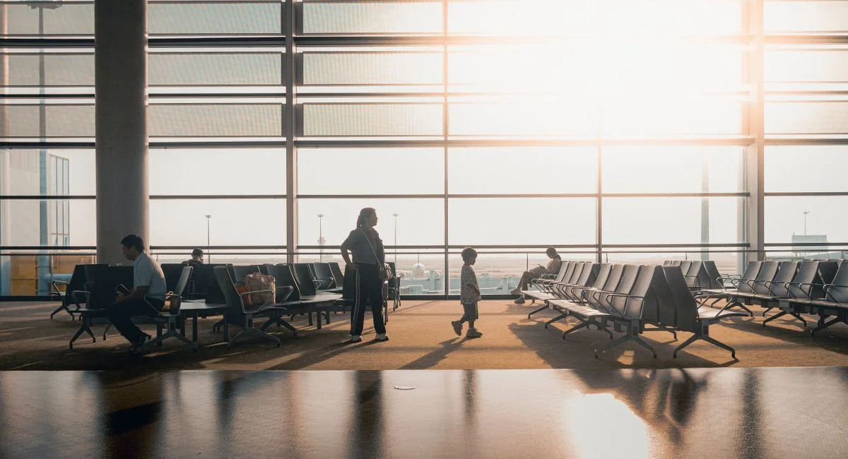 Silhouettes of travelers in a sunlit airport terminal in Shanghai, China.