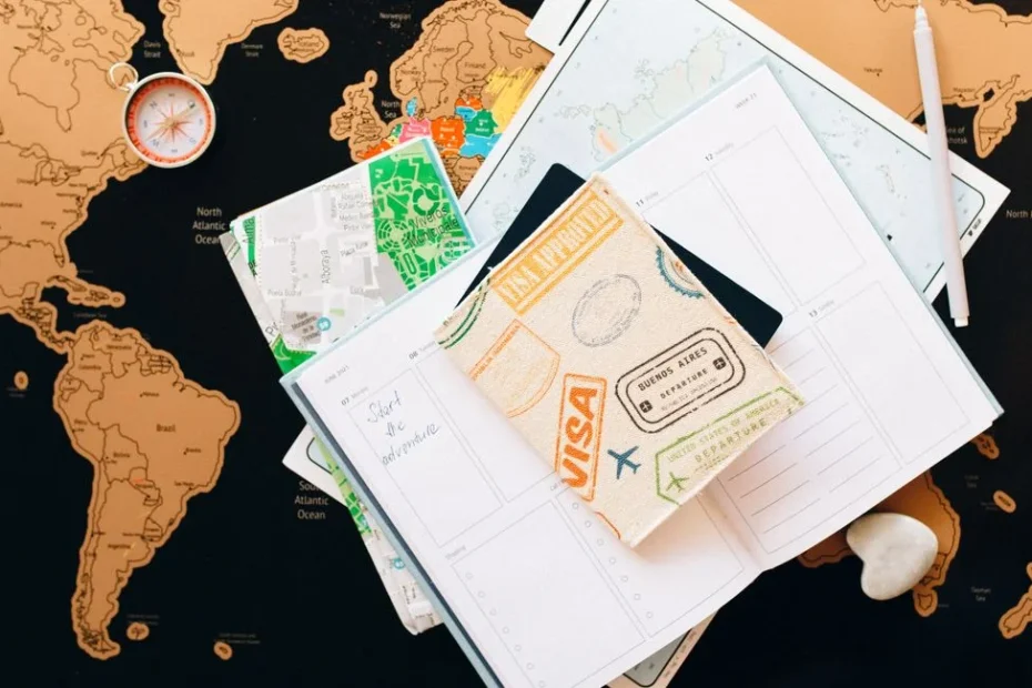 A flat lay of travel planning items on a map, featuring a compass, notebook, and guide for wanderlust enthusiasts.