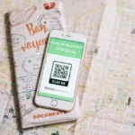 Top view of a smartphone with COVID-19 health passport and travel documents on a map.