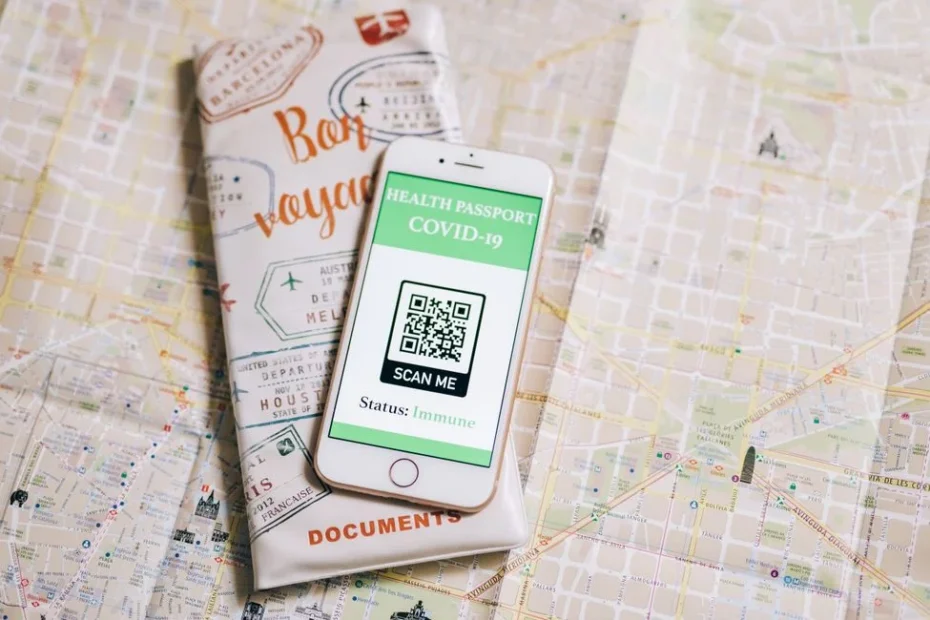 Top view of a smartphone with COVID-19 health passport and travel documents on a map.
